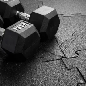 Protective rubber flooring placed under heavy 75 lb dumbbells for safety.